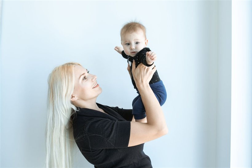 Mother lifting her smiling four-month-old baby at home